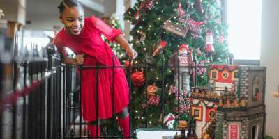 Girl smiling looking down at gingerbread house display at Omni Grove Park Inn