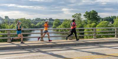 Three women running across a bridge in West Asheville