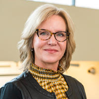 Kelley Hartley Hutton is a Caucasian woman with shoulder-length blonde hair, blue eyes, and glasses