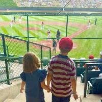 Picture of sister and brother walking down stadium seating towards the front rows of the Little League stadium
