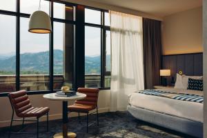 A guest room with a table, chairs, bed and big windows and a view of Chautauqua Park and the Flatirons in Limelight Hotel, Boulder.