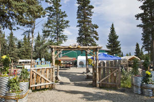 a rustic wooden fence is an entrance to a brewery with an outdoor seating area