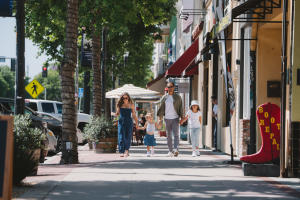 A A family of two adults and two children walk hand in hand towards the viewer as they walk in downtown Girloy