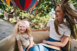 A mother and daughter enjoy a ride at Gilroy Gardens theme park in Gilroy, California, as the girl smiles at the camera.