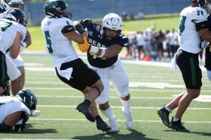 UNC Bears football player tackling a Cal Poly player to the ground
