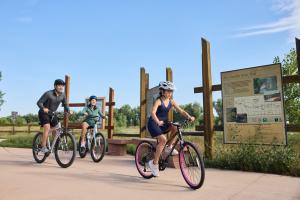 Family Biking outdoors on the Poudre River Trail with sign behind them