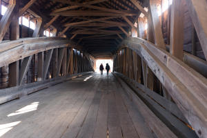 Two people walking through the covered bridge