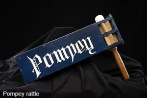 A football rattle made of wood with a blue bit with the word Pompey in write lettering on it.