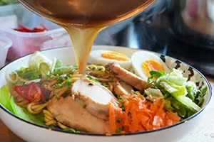 Image shows broth being poured onto a ramen dish