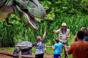 Man giving presentation about dinosaurs at Reptiland with people in the foreground watching.