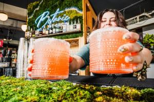 A woman serves two drinks at the bar inside GROW Plant Bar