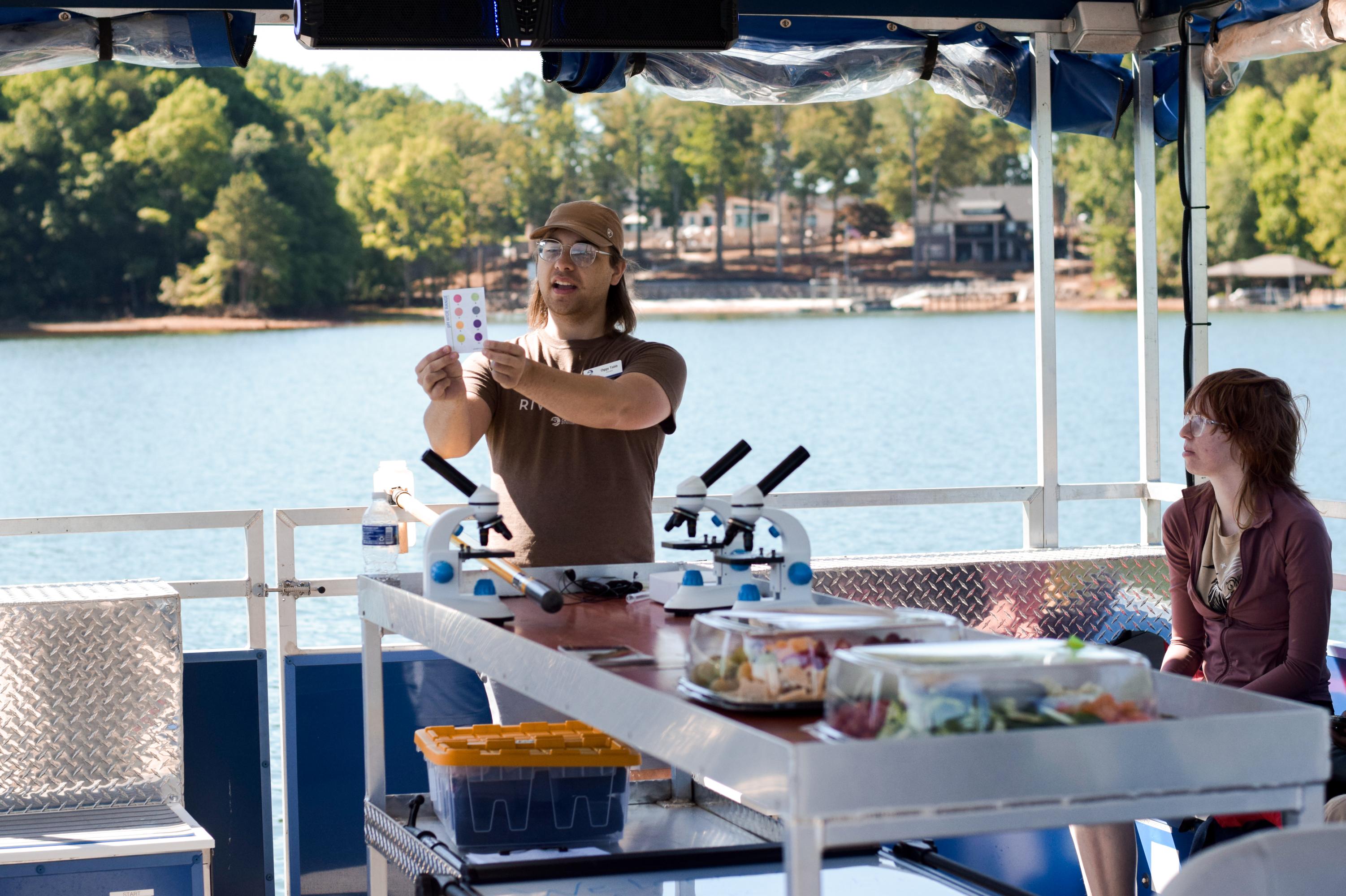 Environmental scientist holding up a pH level indicator card on the Catawba Riverkeeper Floating Classroom on Lake Norman