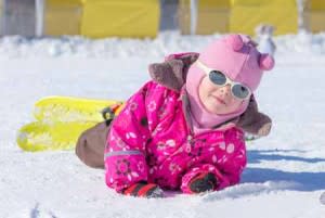 Child laying in snow with skis on | Shutterstock
