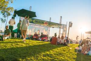 Oakland visitors sitting on the lawn in front of the Main Stage