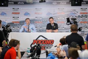 Two men sitting at a long table with microphones at a press conference