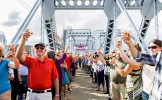 Large crowd toasting with wine glasses on the Purple People Bridge