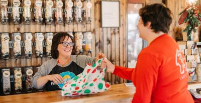 Cashier handing customer their purchase in a holiday bag at Mom's Popcorn