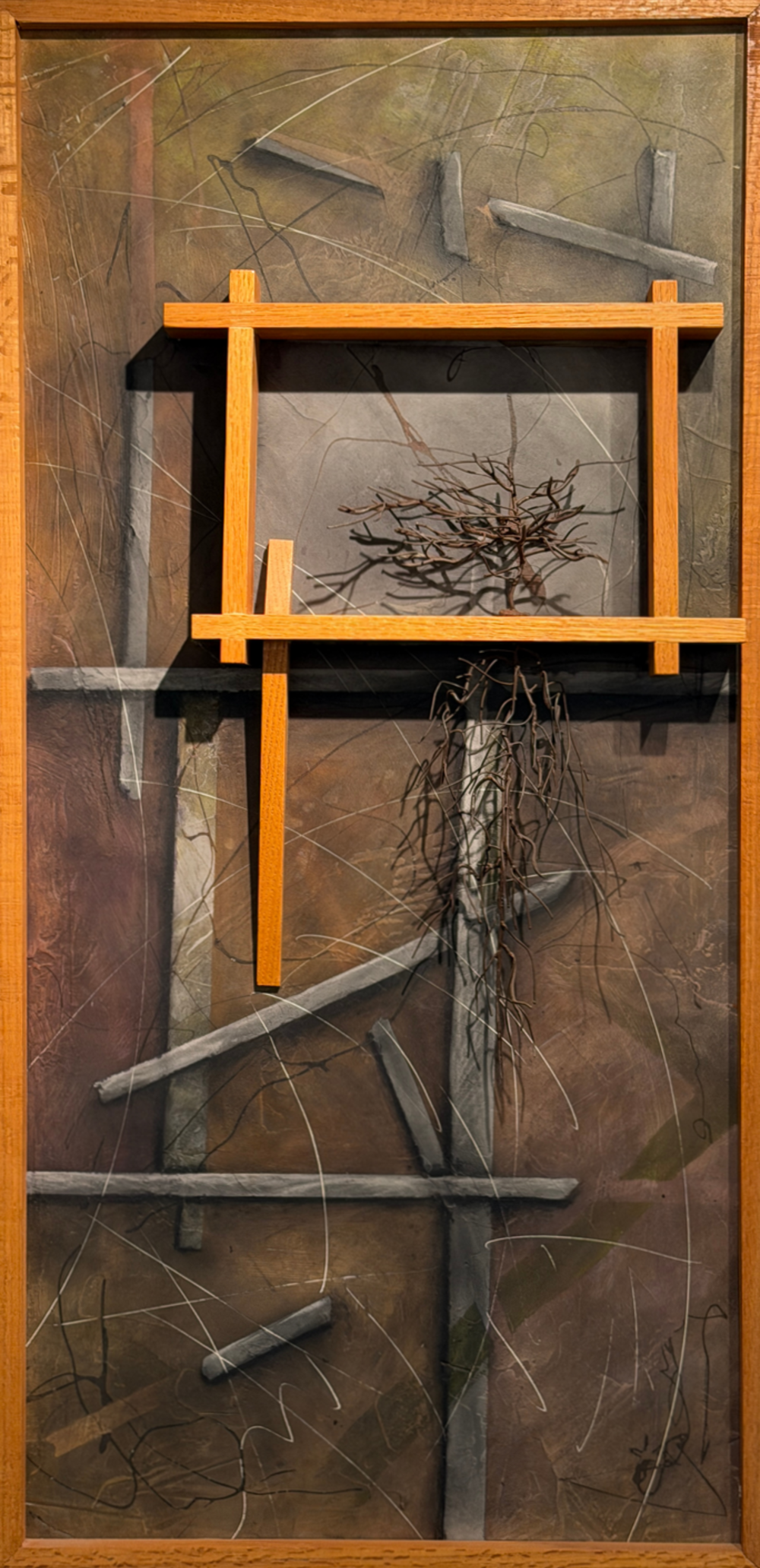 An abstract art piece of what looks like a shattered telephone pole, and tree branches have taken over the top of it. The branches are framed by thick wooden beams.