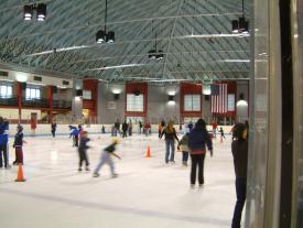An open skate session with people ice skating in groups around the rink.