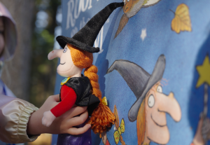A youngster holds up a doll of the witch from Room on the Broom, next to one of the boards along the Room on the Broom trail at Cannock Chase Forest, Staffordshire.