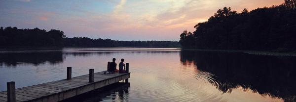 Couple sitting on a dock at sunset