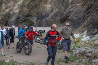 Many people at the Cannon Beach Fat Bike Festival walking their bikes around coastal rocks toward Hug Point.