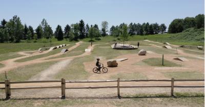 Carver Lake Bike Park outdoor trail showing bikers maneuvering different skill challenges.