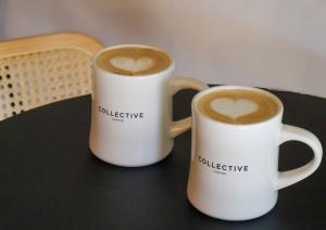 Two mugs of coffee sitting on a black table.