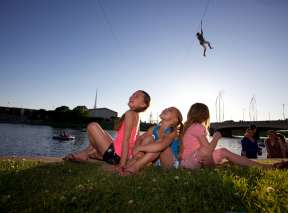 Three young girls watching someone zipline over the Arkansas River in downtown Wichita