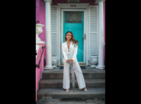 A woman poses on the steps of a pink building on Oakland Avenue