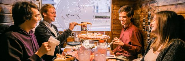 A group of four people sharing a pizza at Mother Bear's Pizza