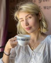 writer Natalie La Flare holding coffee cup and winking at camera