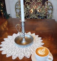 Picture of Latte on table beside candle with fireplace in the background