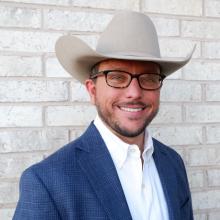 caucasian man with glasses wearing a tan cowboy hat