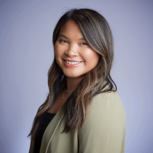 Jackie Headshot - Laotian woman with dark brown hair and sparse blonde highlights wearing a light olive green blazer and black shirt