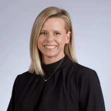 stephanie headshot - caucasian woman with short blond short and blue eyes where a long sleeve black shirt that has a short turtleneck