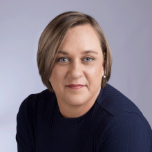 Kashion headshot - caucasian woman with short light brown hair and blue eyes wearing a long sleeve dark blue shirt