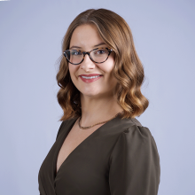 Hope headshot - Caucasian woman with curly, light brown hair and brown eyes wearing brown and wearing glasses