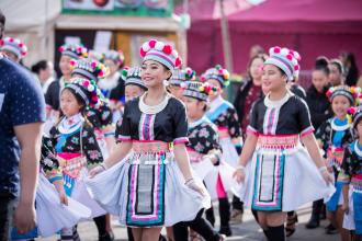 Girls dressed in colorful dresses and hats perform during parade