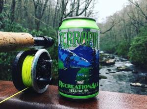 A can of Terrapin beer alongside a fishing reel with a stream in the background