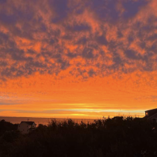 An orange, peach and purple sunset sky over the sound waters on the Outer Banks.