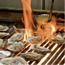 Oysters on the half shell on a grill with flames.