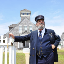 James Keeper leans on a fence post in front of the Chicamacomico Lifesaving Station in Rodanthe, NC.