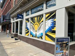 The exterior of the store Runners' Wings in Frostburg, MD, which features a mural of a sun and rays, with large painted white wings with shades of blue feathers.