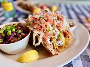 A plate of fish tacos with a side of black beans.