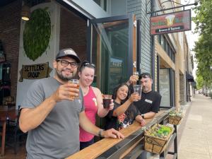 Four people sitting outside and cheering with beers at Settle Down
