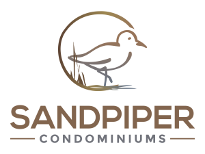 Outline drawing of a sandpiper by the shore in a brown/gold color. Text underneath reads "Sandpiper Condominiums"