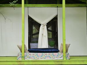 Glamping tent on a lime green painted platform with a floral bed and white tent
