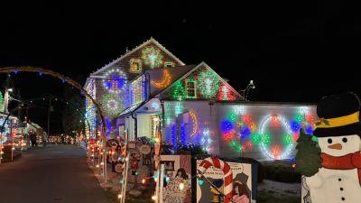House at Koziar's Christmas Village lit up with Christmas lights with a snowman in the front