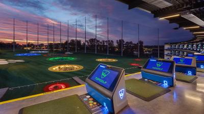 Golf bays at Topgolf Woodbury with sun setting in the background